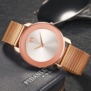 Close-up of ultra-thin rose gold mesh watch on a navy leather wallet with minimalist dial