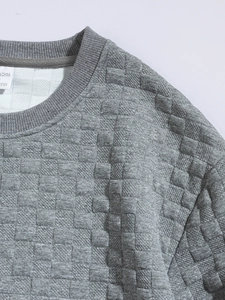Close-up of gray sweatshirt neck and shoulder showing checkered embossed fabric texture
