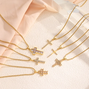 Gold stainless steel cross necklace set with sparkling cubic zirconia on silk fabric