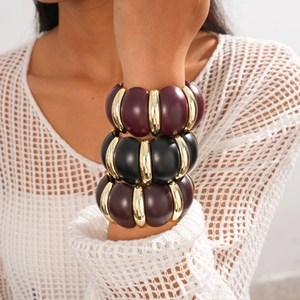 Close-up of stacked acrylic geometric bracelet in burgundy, black and gold tones