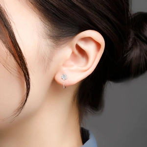 Close-up of minimalist silver flower earring with thin circular hoop on female model
