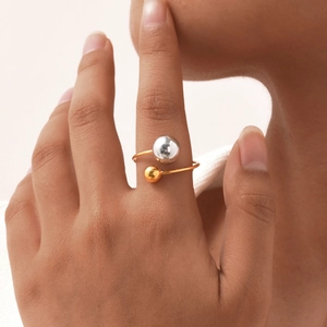 Macro detail of an adjustable stainless steel open ring with gold and silver bead accents