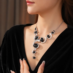 Elegant geometric silver necklace with black stones worn on a velvet top V-neckline