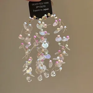 Détail de boucles d'oreilles à pompons colorés avec paillettes et argent S925