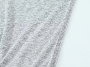 Detail of grey knitted cotton fabric showing texture and reinforced seam stitching