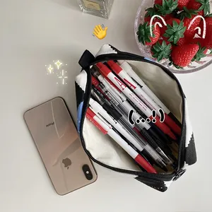 Top view of a high-capacity checkerboard pencil case with pens and lifestyle props
