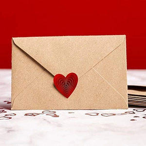 Detail of red heart-shaped sticker sealing a brown kraft envelope for gift decoration