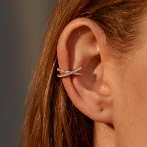 Close-up of golden X-shaped ear cuff with micro-pave zircons on woman's ear