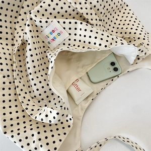 Internal view of beige polka dot canvas tote bag showing large capacity and label detail