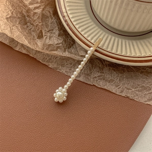Detailed view of pearl gold bobby pin hair clip on vintage aesthetic background