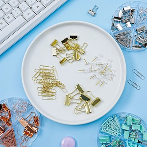 Pastel binder clips and paperclip set in a white round tray on light blue background