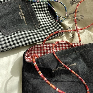 Detail of denim tote bags featuring vibrant beaded straps and colorful grid linings