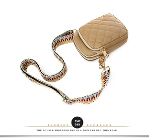 Close-up of khaki quilted crossbody bag with colorful geometric woven strap and gold zippers