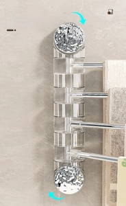 Close-up of vacuum suction mount and rotating multi-bar towel rack on marble wall