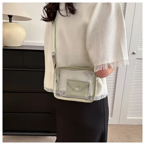 Detail of light green transparent jelly bag with wide shoulder strap worn by a model