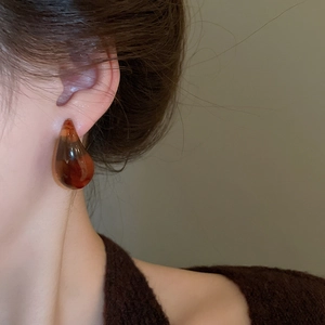 Close-up of teardrop-shaped leopard print resin earrings with retro amber texture style