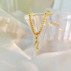 Close-up of gold titanium steel box chain necklace with italic letter pendant
