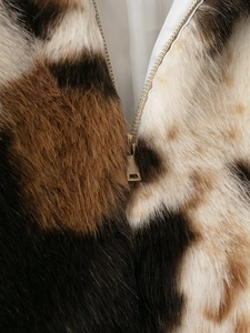 Détail macro du zip de la veste en fausse fourrure avec motif animalier noir et marron