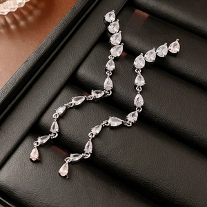 Detailed shot of silver teardrop zircon tassel earrings on black leather texture