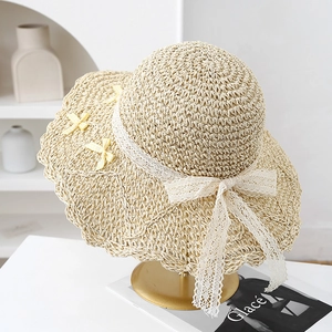 Detailed view of straw sun hat with white lace bow and yellow accent on golden stand