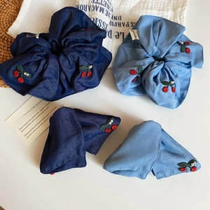 Detailed shot of fabric scrunchies with cherry embroidery, pearls and Happiness tags