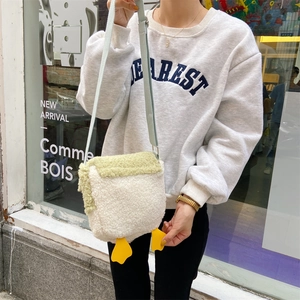 Cute lamb wool duck crossbody bag shown on a model in a stylish store setting