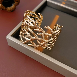 Detailed macro view of the hollow coral-shaped open cuff bracelet in a golden finish