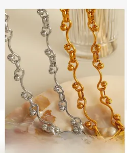 Detailed close-up of gold and silver wave-link metal jewelry on a shell tray