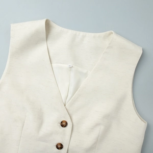 Detail view of v-neck vest showing textured linen fabric and tortoise buttons