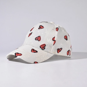 Detailed close-up of lace textured white baseball cap with red heart embroidery