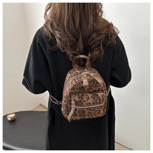 Close-up of stylish leopard print mini backpack worn on model's back in minimalist interior