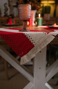 Detail of red and cream woven Christmas table runner with tassels on a wooden table
