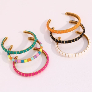 Detail of multi-colored enamel open bangles with 18K gold plating on a pink background