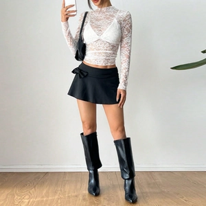 Full-body shot of a white lace long-sleeve top paired with a black mini skirt and boots