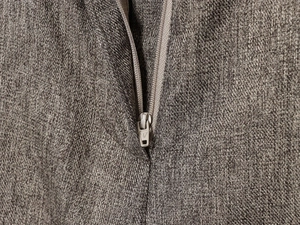Close-up of metal zipper and coffee brown herringbone twill fabric on trousers