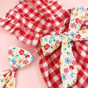 Macro detail of red plaid dog dress with floral bow tie and cotton fabric texture