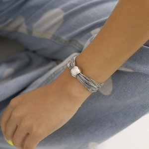 Close-up of a silver multi-layer chain bracelet with a smooth ball clasp worn on a wrist