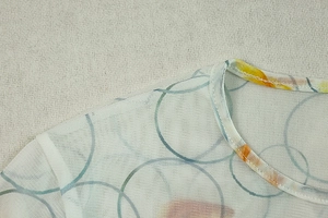 Detail of round neckline and breathable mesh fabric with vibrant orange and blue prints