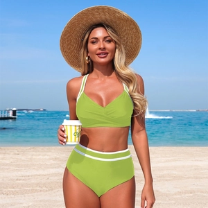 Detail of green two-piece bikini with white stripes and high waist cut on a beach