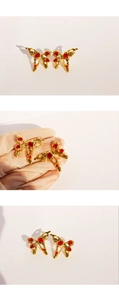Macro shot of gold butterfly earrings with red gemstones and liquid metal texture