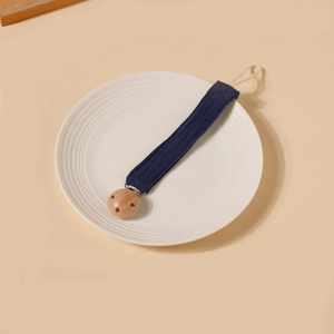 Détail de l'attache-tétine en coton bleu foncé avec pince ronde en bois de hêtre naturel