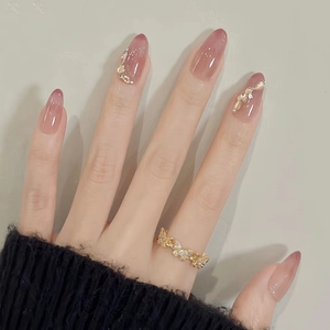 Détail de faux ongles œil de chat ovales rose nude avec feuille d'or et bague nœud