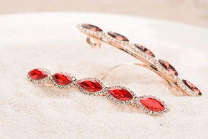 Close-up of vintage hair clip with marquise-cut red and amber crystals in gold setting
