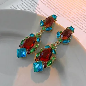 Vintage water drop earrings with colorful crystals and gold-plated finish on a magazine