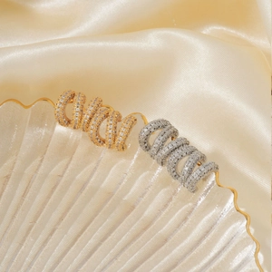 Luxuriöse Spiralohrringe mit Mikrozirkonia in Gold und Silber auf Glasschale
