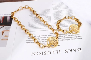 Dettaglio di collana e bracciale a catena dorata con ciondoli Albero della Vita su rivista