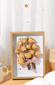 Detailed view of hollow wooden DIY shadow box frame with yellow dried roses and pink ribbon