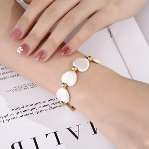 Détail des perles en nacre en forme de cœur et des perles dorées sur un bracelet élégant