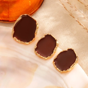 Macro detail of irregular pebble-shaped jewelry with brown glaze and gold-tone metal edges