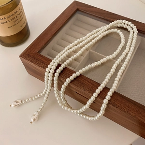Long collier de perles vintage français avec pendentif baroque sur un coffret à bijoux